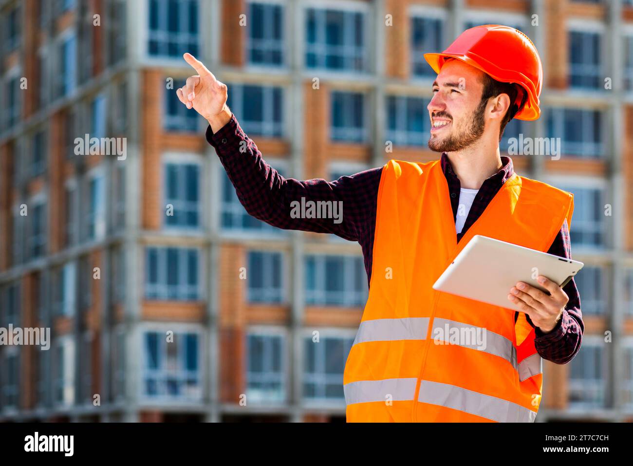 Medium shot portrait smiling architect pointing away Stock Photo