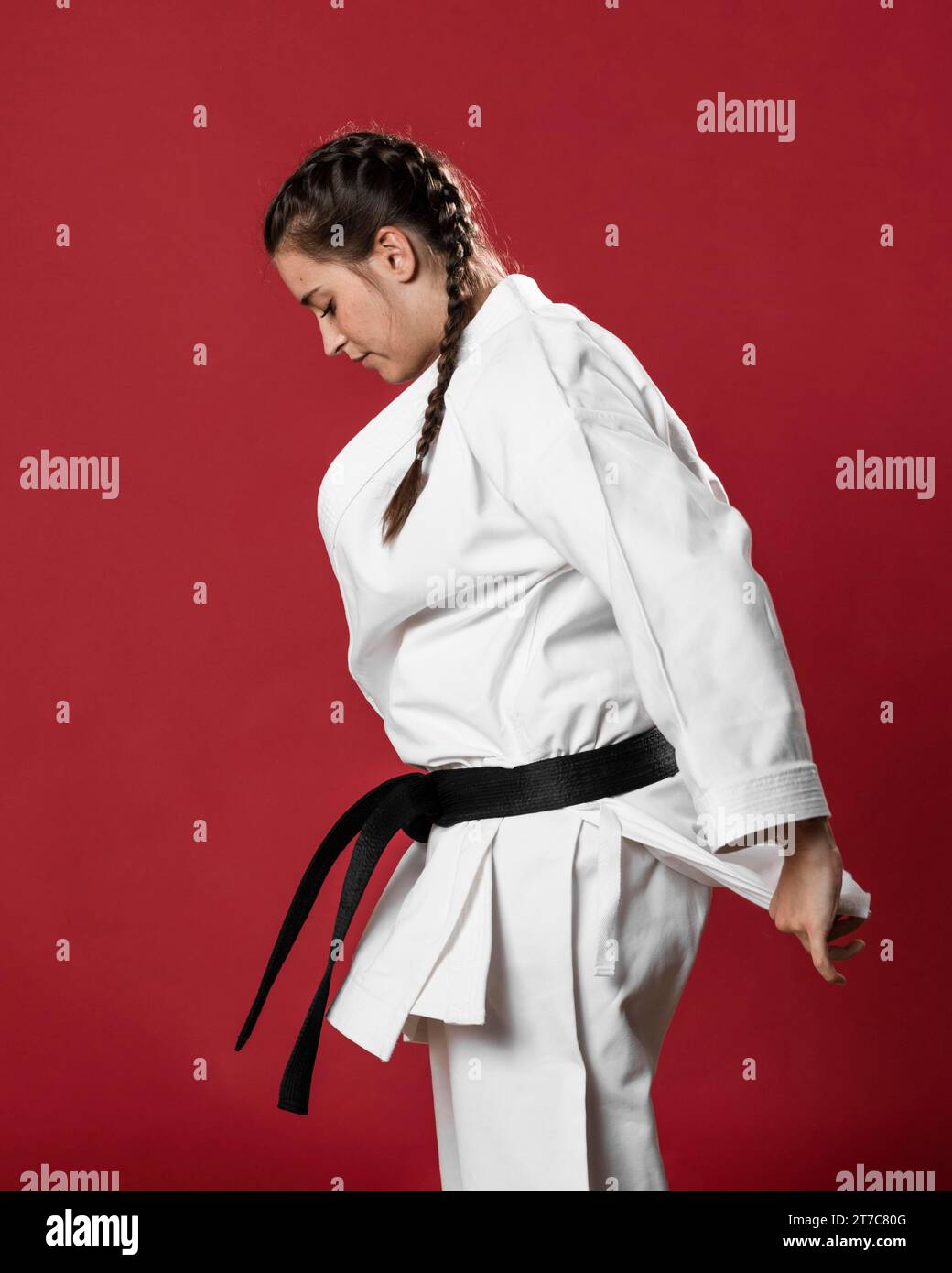 Sideways karate woman traditional white kimono red background Stock Photo