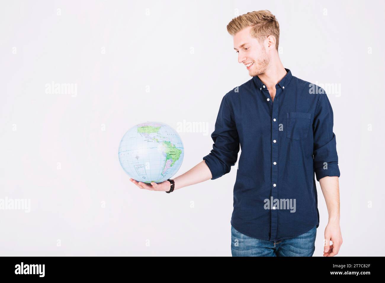 Smiling young man looking globe Stock Photo