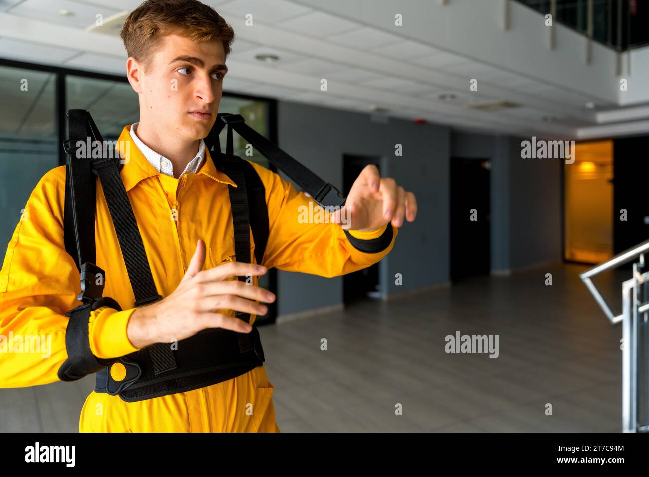 Employee with an exoskeleton from a futuristic high-tech warehouse, stretching to test the suit, help to improve injuries, futuristic physiotherapy Stock Photo
