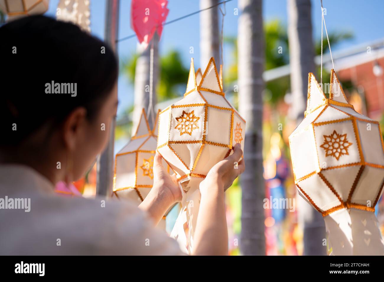 A beautiful and happy Thai-Asian woman is hanging a paper lantern and enjoying YI Peng or Loy Krathong festival at a temple in Chiang mai. Thai-Lanna Stock Photo