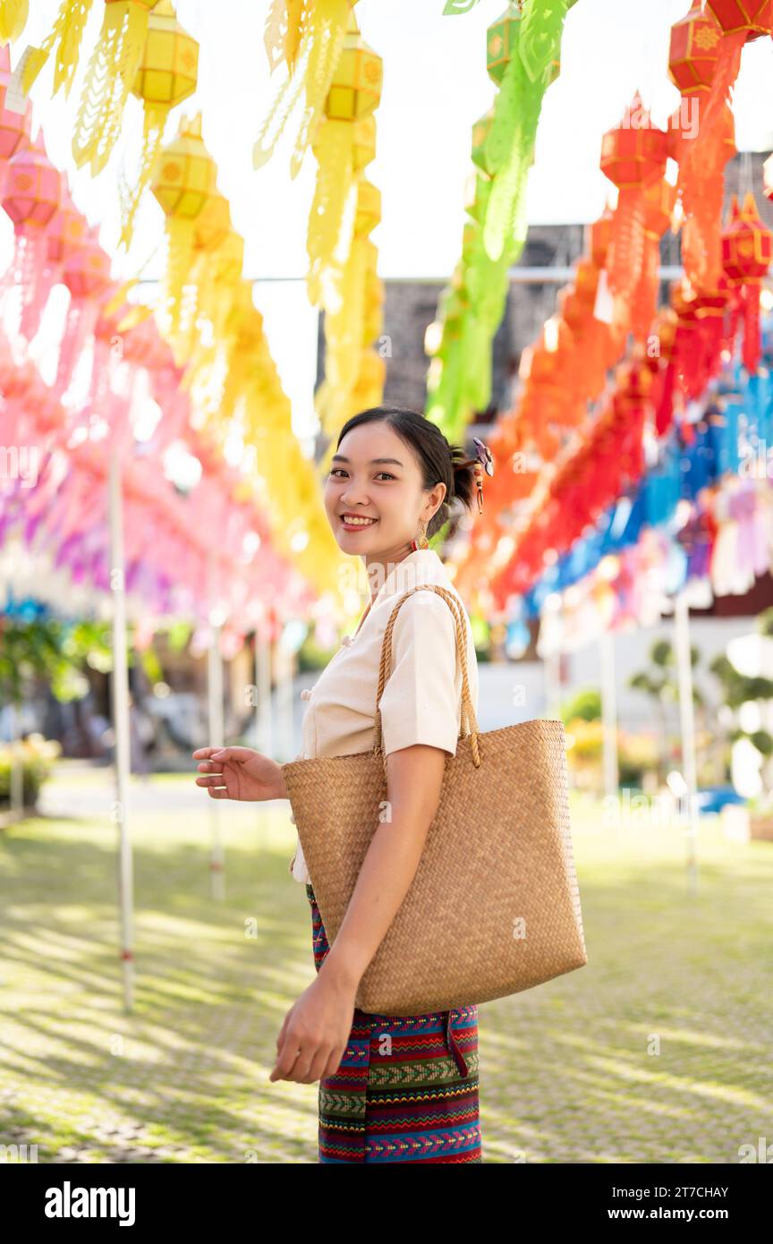 A beautiful and happy young Asian-Thai woman in a traditional Thai-Lanna dress is enjoying in a Thai-Lanna lantern festival or Yi Peng at a temple in Stock Photo