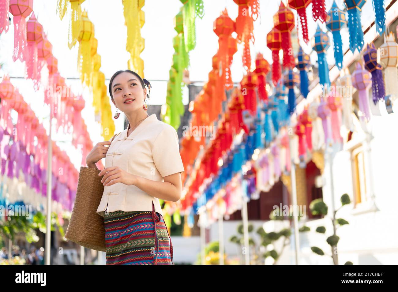 A beautiful and happy young Asian-Thai woman in a traditional Thai-Lanna dress is enjoying in a Thai-Lanna lantern festival or Yi Peng at a temple in Stock Photo