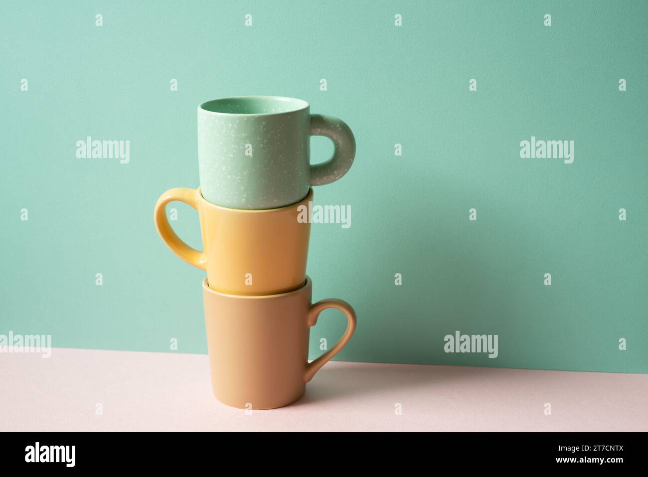 Stack of mug cup on pink table. mint green wall background Stock Photo