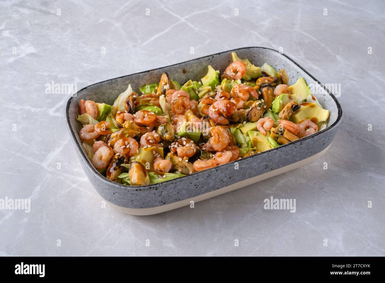 Bowl with iceberg lettuce salad with shrimp, mussels and avocado Stock Photo