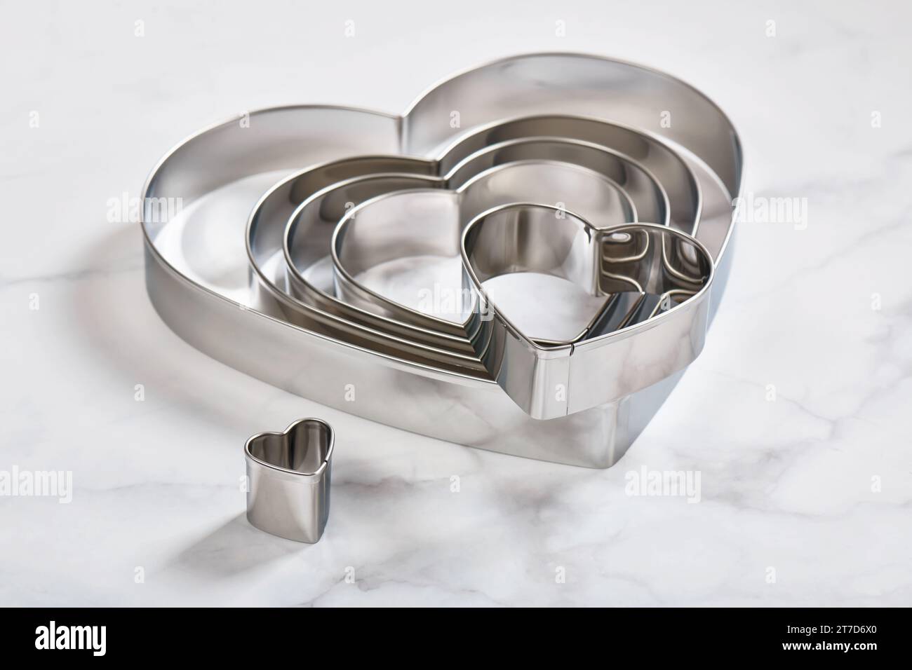 Set of stainless steel heart-shaped cookie cutters on a white marble ...
