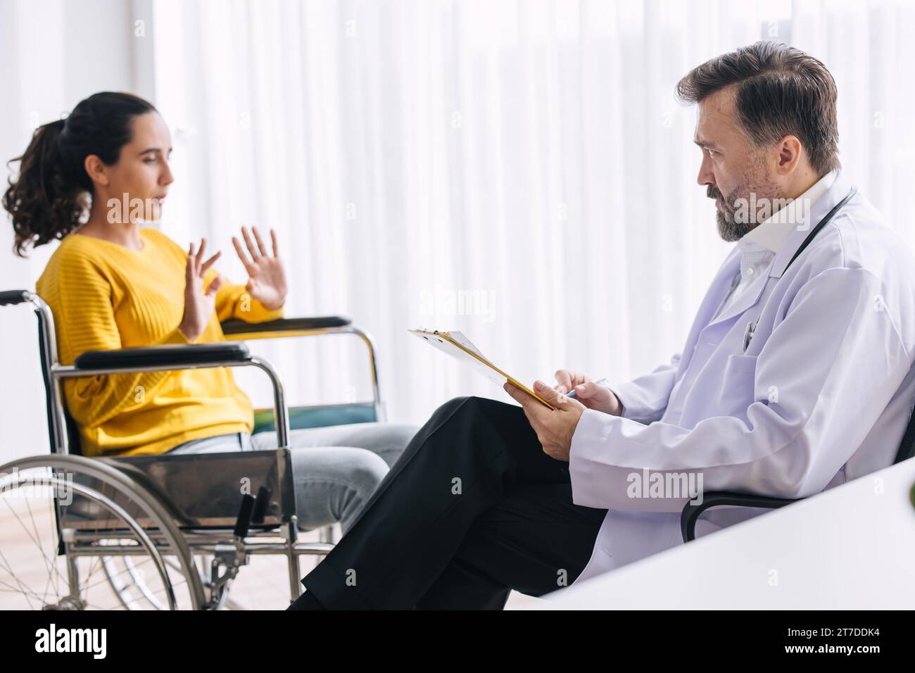 Psychiatrist doctor collect data talk with patient on wheelchair for mental care health problems check followup in hospital clinic Stock Photo