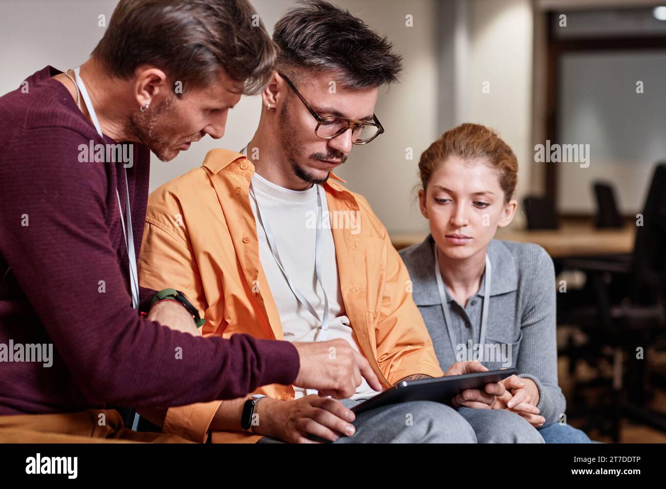 Business colleagues working on tablet pc in team while sitting in office Stock Photo