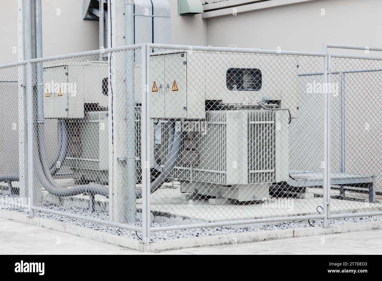 Electricity transformer high voltage Three phase electric power with safety area fence protection zone in industry building. Stock Photo