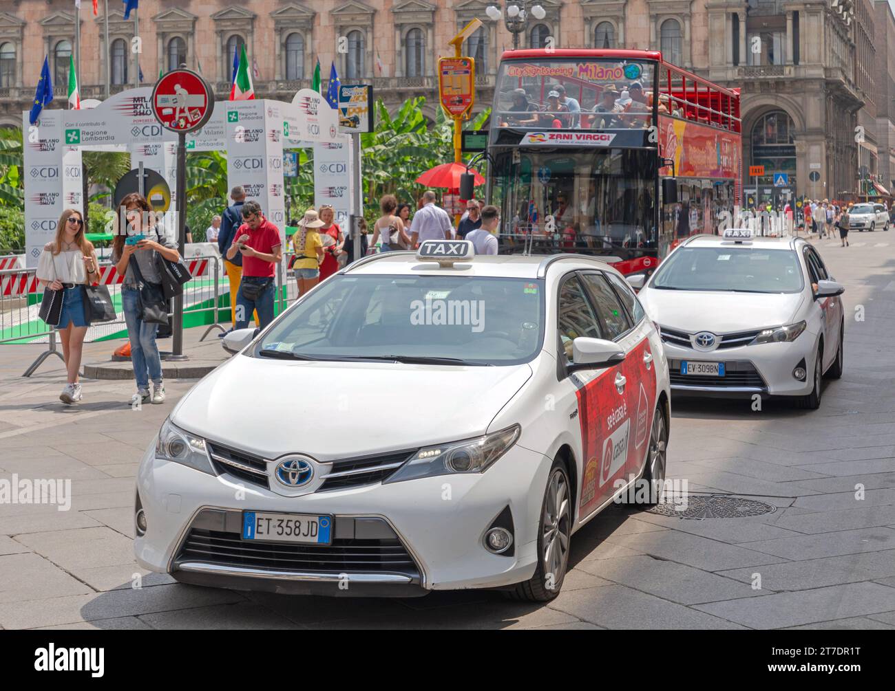Milan, Italy - June 15, 2019: White Hybrid and Electric Taxi Vehicles at Street in City Centre at Summer Day. Stock Photo