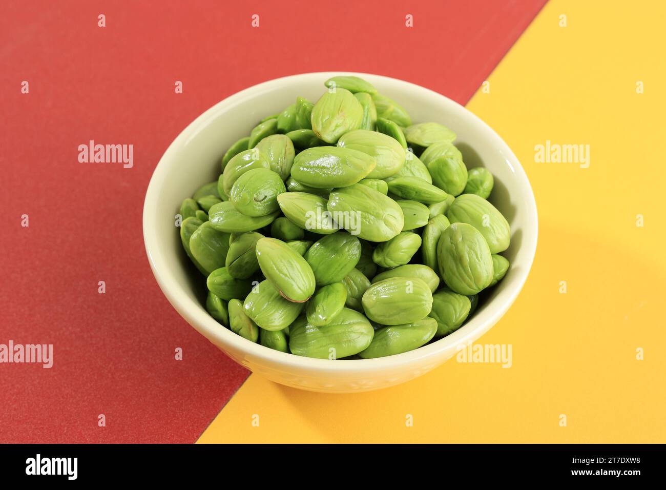 Raw Peeled  Petai or Pete Parkia speciosa. Known as Stinky Bean or Bitter Bean. On Red and Yellow Background Stock Photo