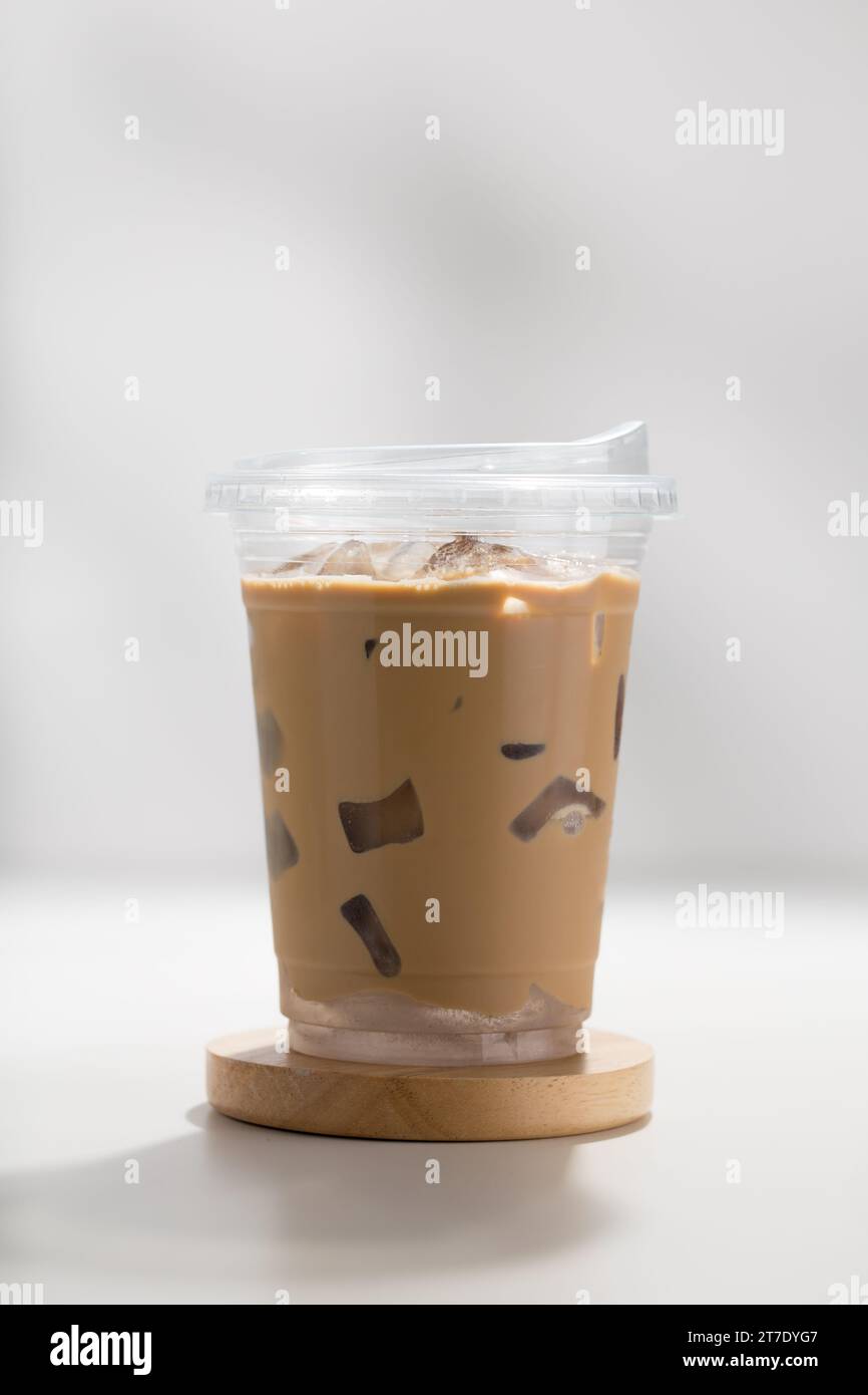 Iced cappuccino in a plastic glass on a white wooden table, minimalist ...