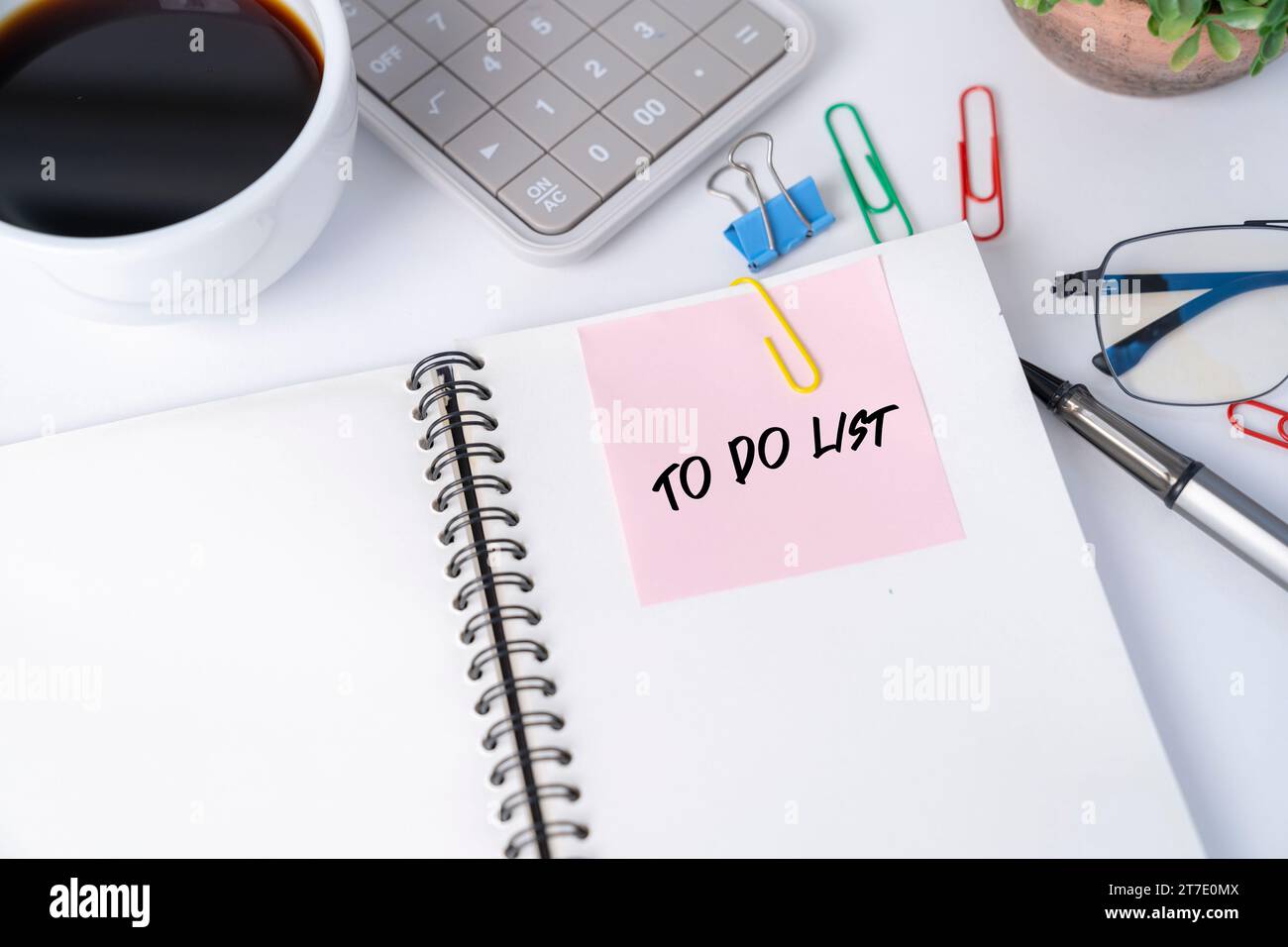 Office desk with pink sticker on notebook. Stock Photo