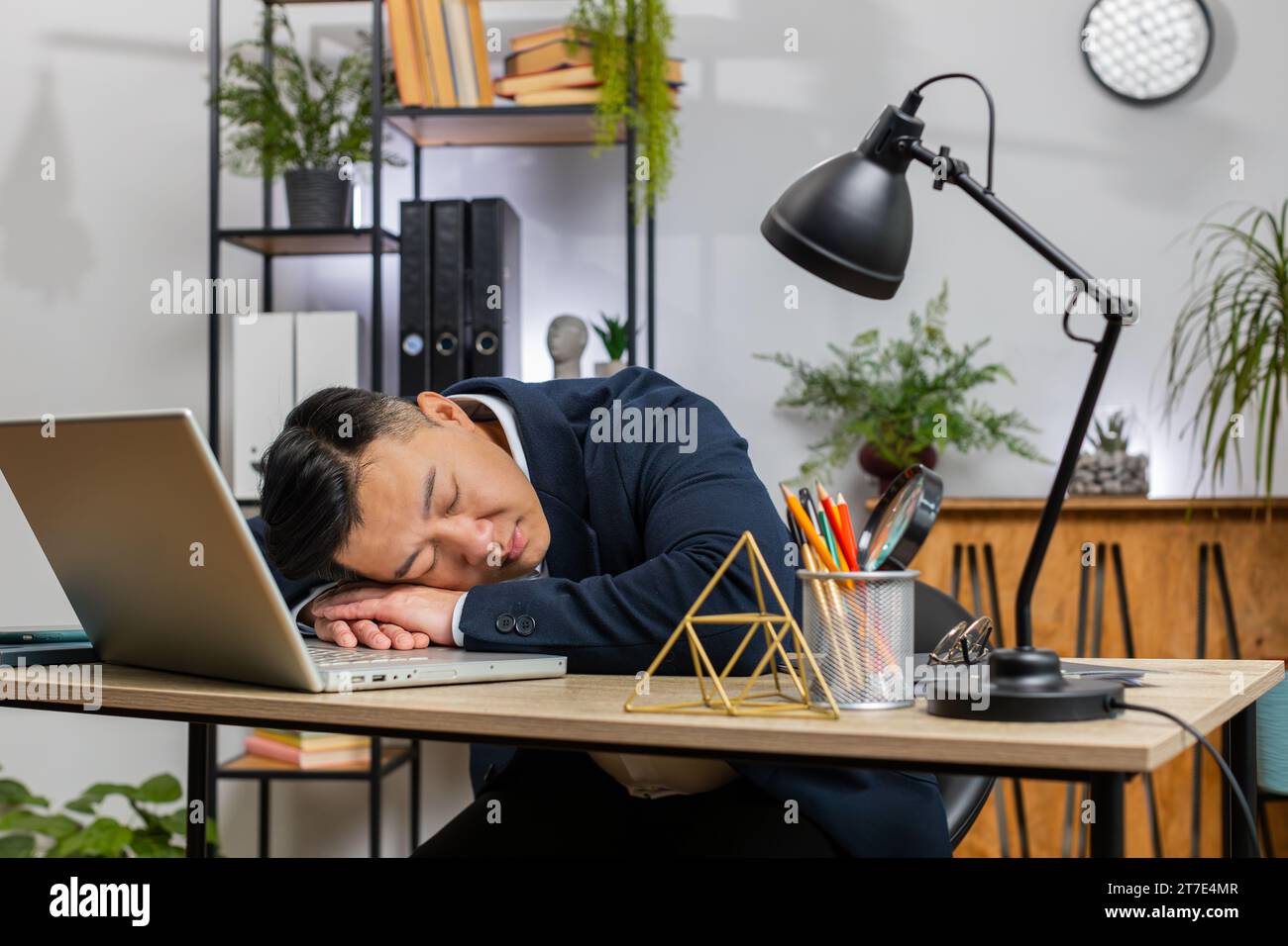 Bored sleepy Asian businessman worker working on laptop computer