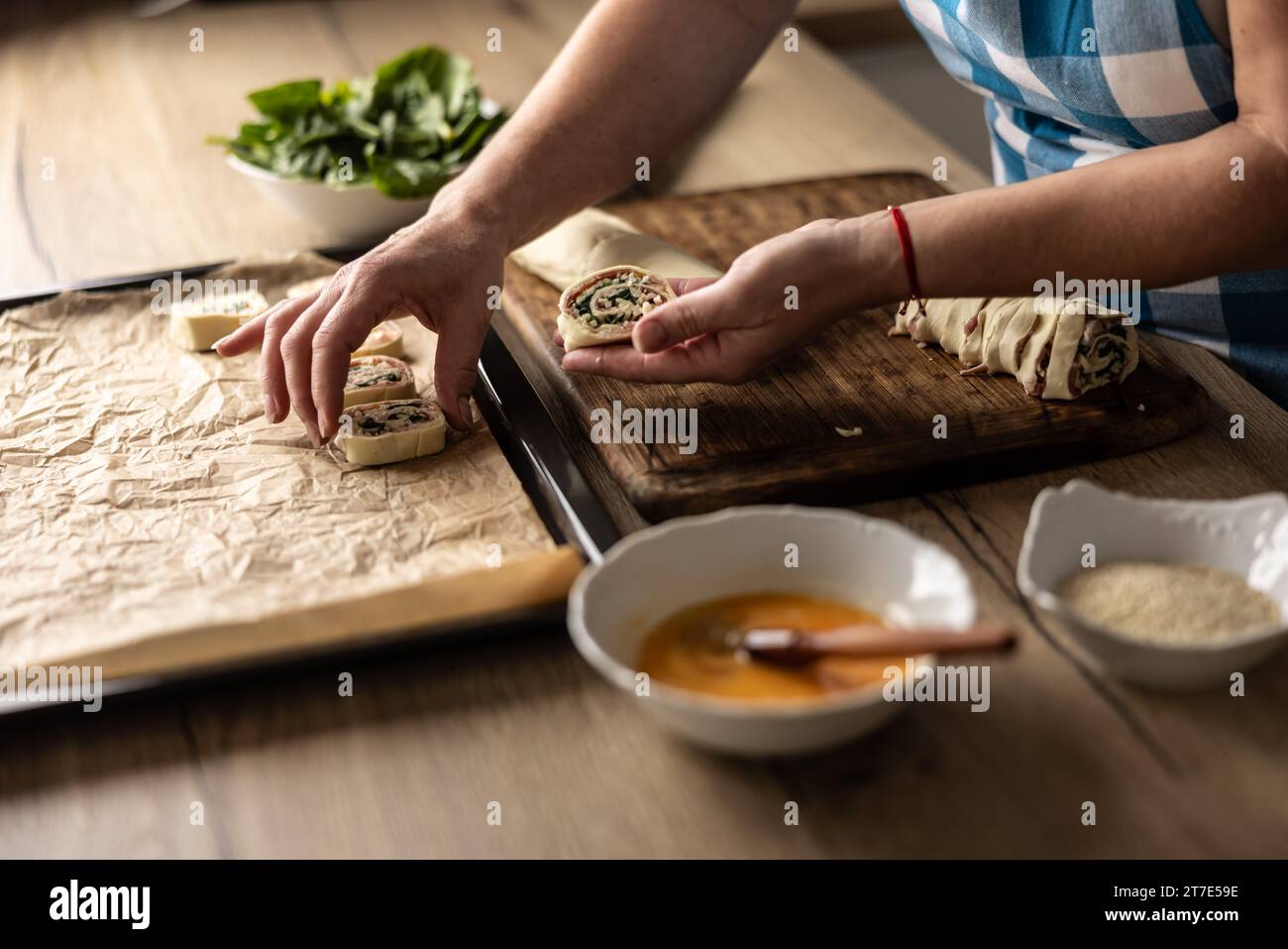 The cook places raw mini puff pastry cookies on a baking sheet. Recipe
