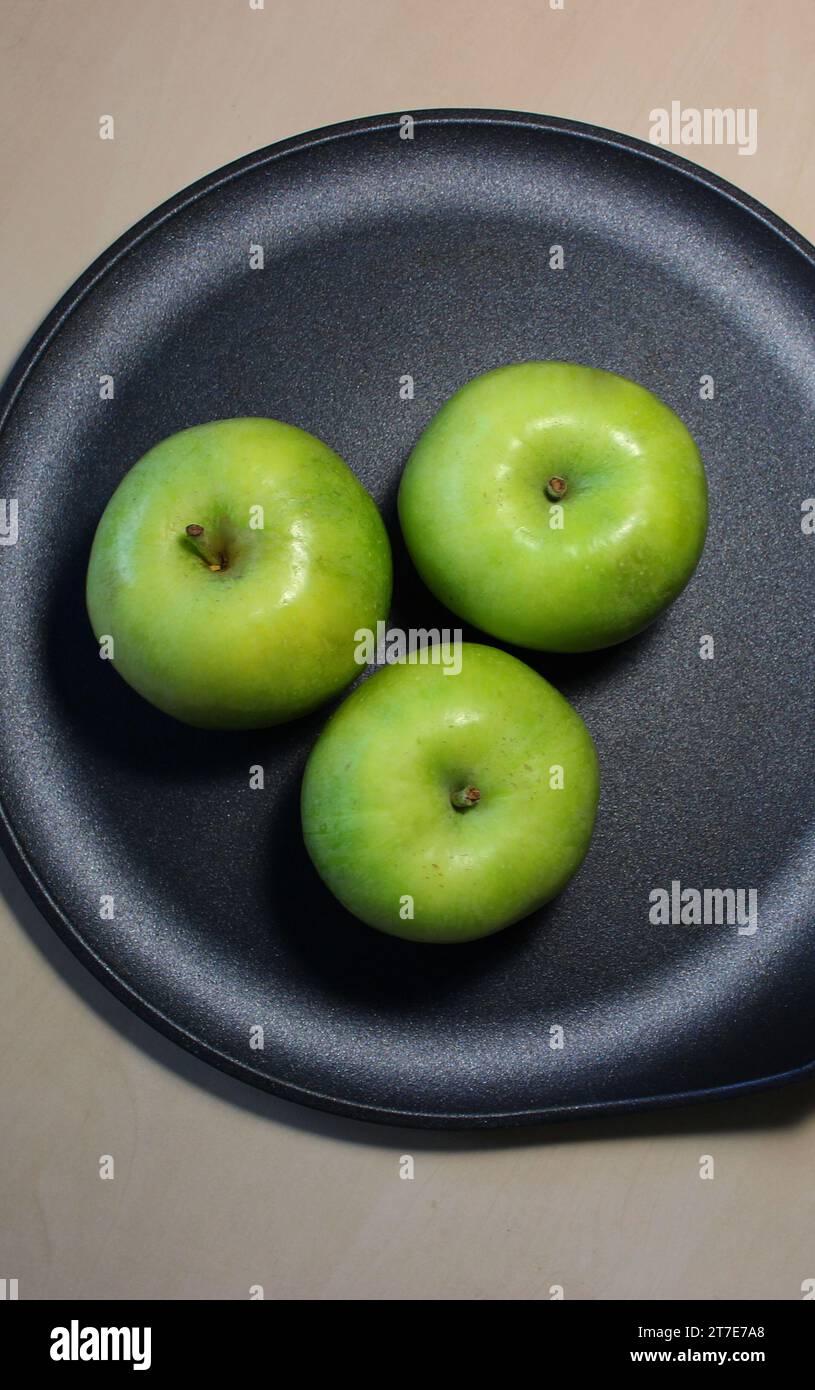 Three whole Granny Smith apples ready to be baked in a special pan Stock Photo