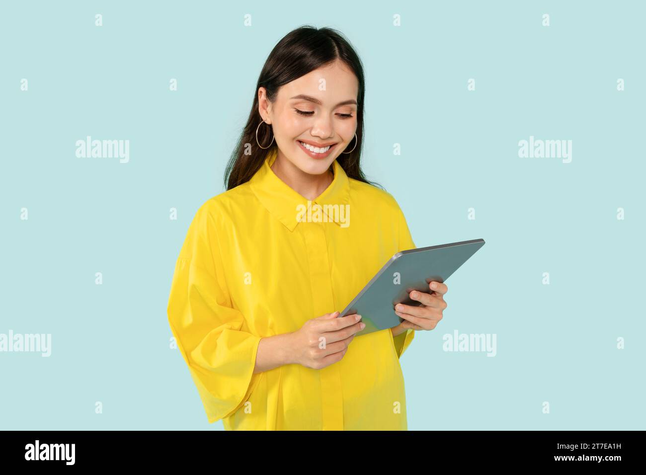 Cheerful young woman using digital tablet on blue Stock Photo