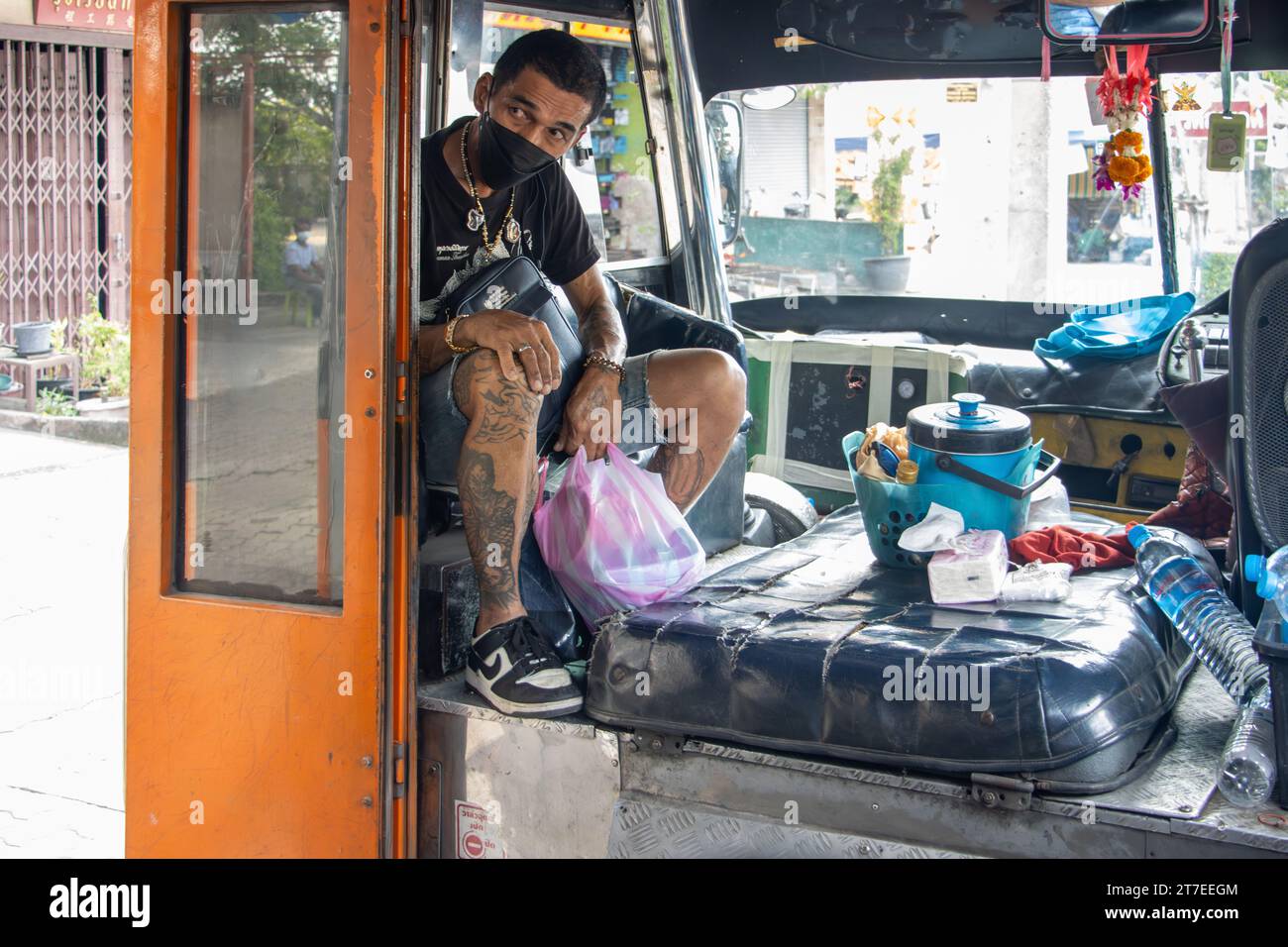 BANGKOK, THAILAND, OCT 28 2023, A passenger sits above the engine in the front of an old city bus Stock Photo