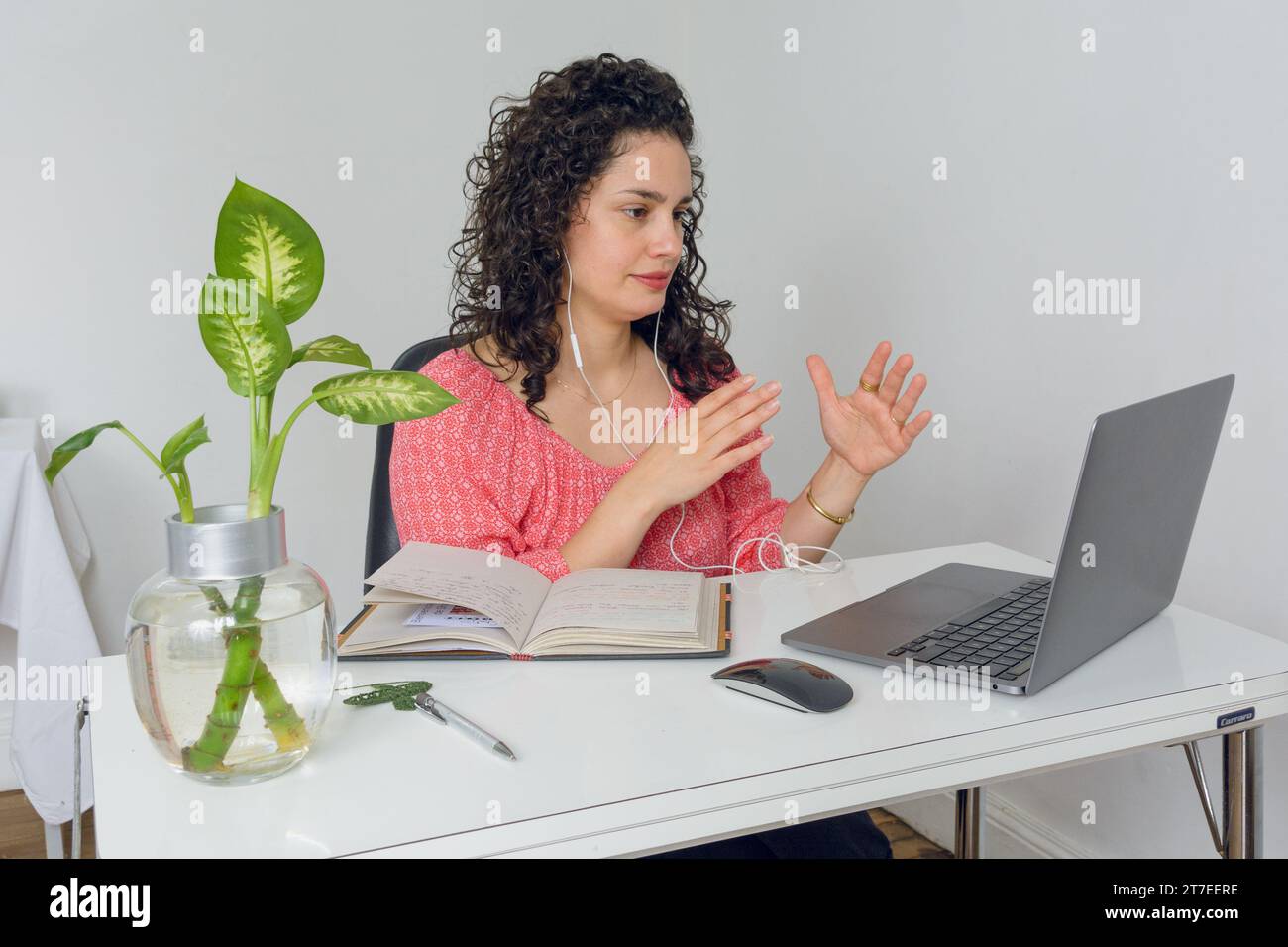 young latin business woman sitting in her office talking on call online ...