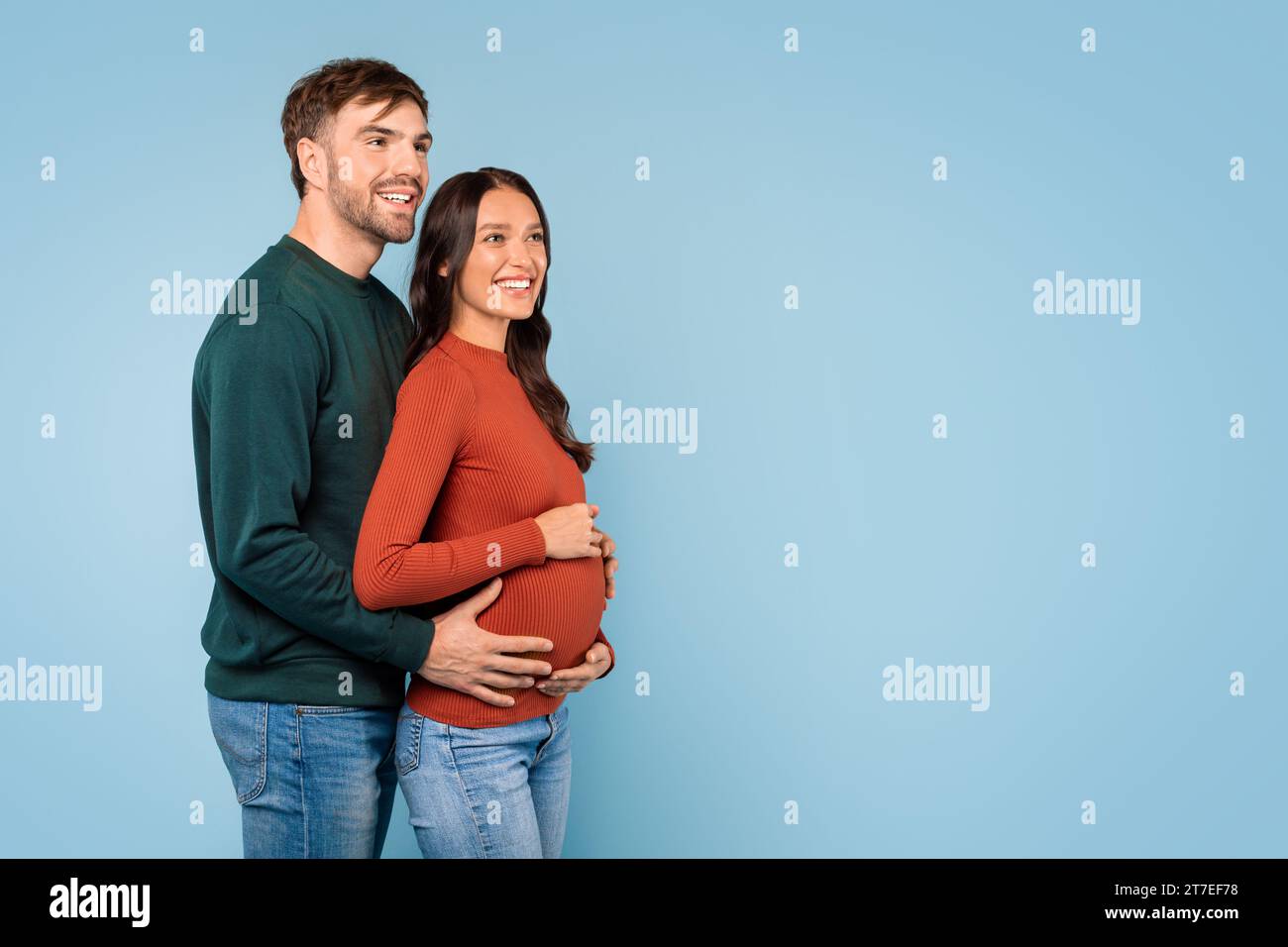 Man hugs pregnant wife, looks together at free space Stock Photo - Alamy