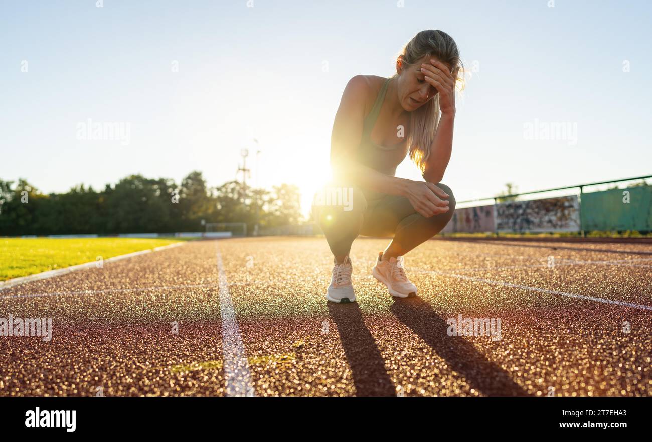 Distressed female athlete resting on a running track Stock Photo - Alamy