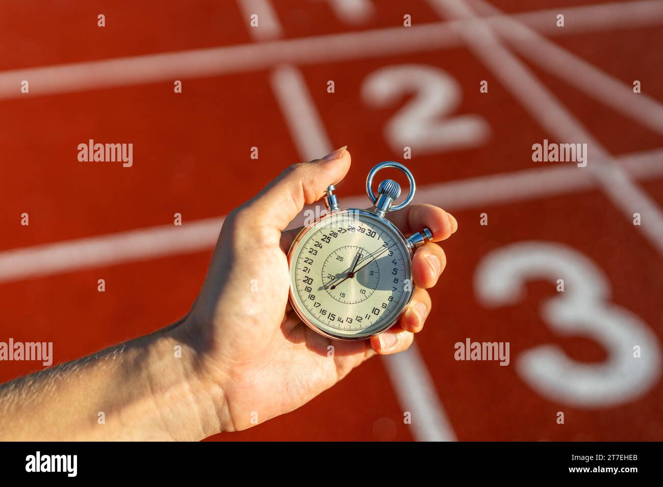 Stopwatch in hand, track numbers background, timing, sports, competition, measuring performance
