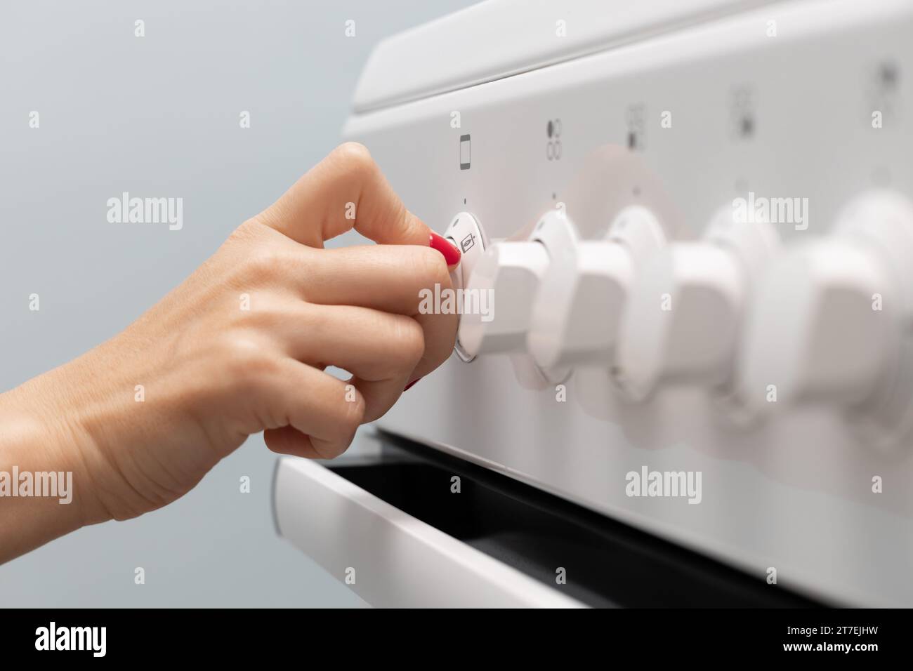 woman turns on the oven in a gas stove. woman's hand turns on the oven