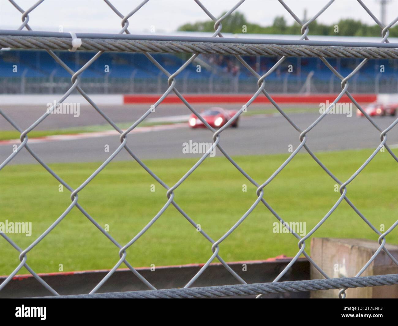 blurred racing cars and stands seen through in focus wire fence Stock ...
