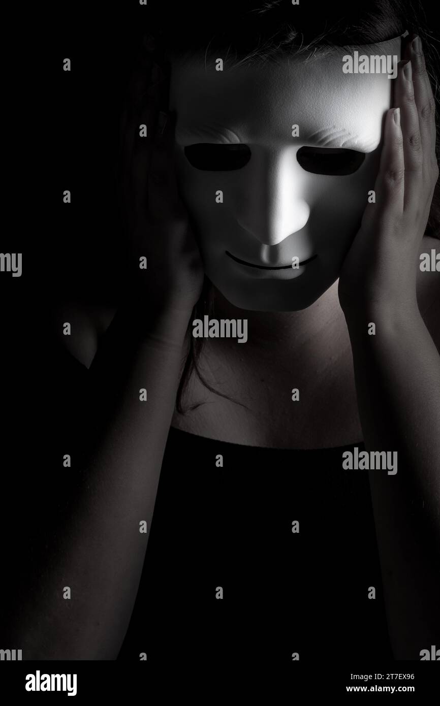 Image in black and white in vertical format where there is a young girl holding a mask that