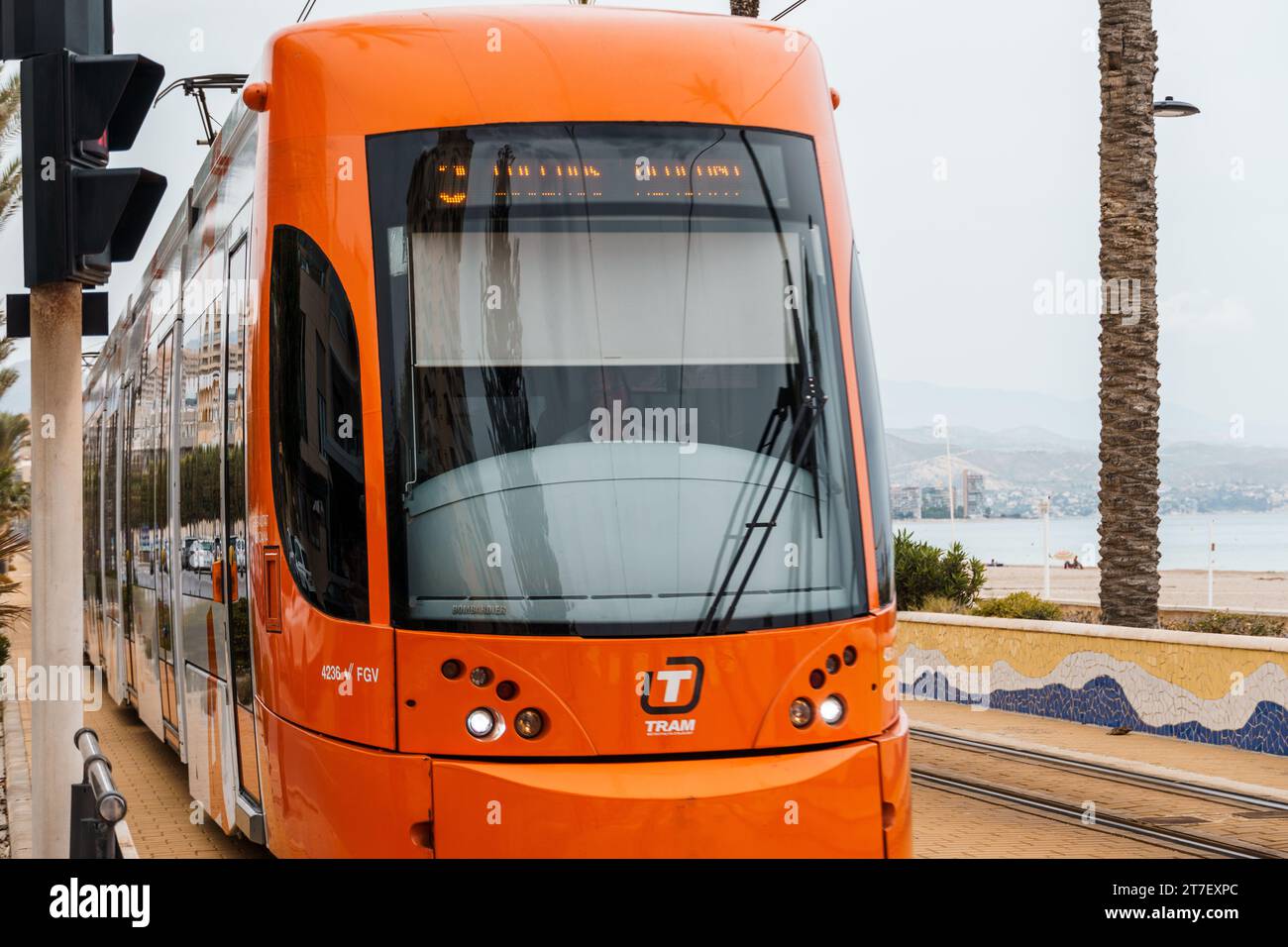 Alicante, Spain - October 14, 2023: Orange streetcar running along the promenade between Alicante and San Juan Stock Photo
