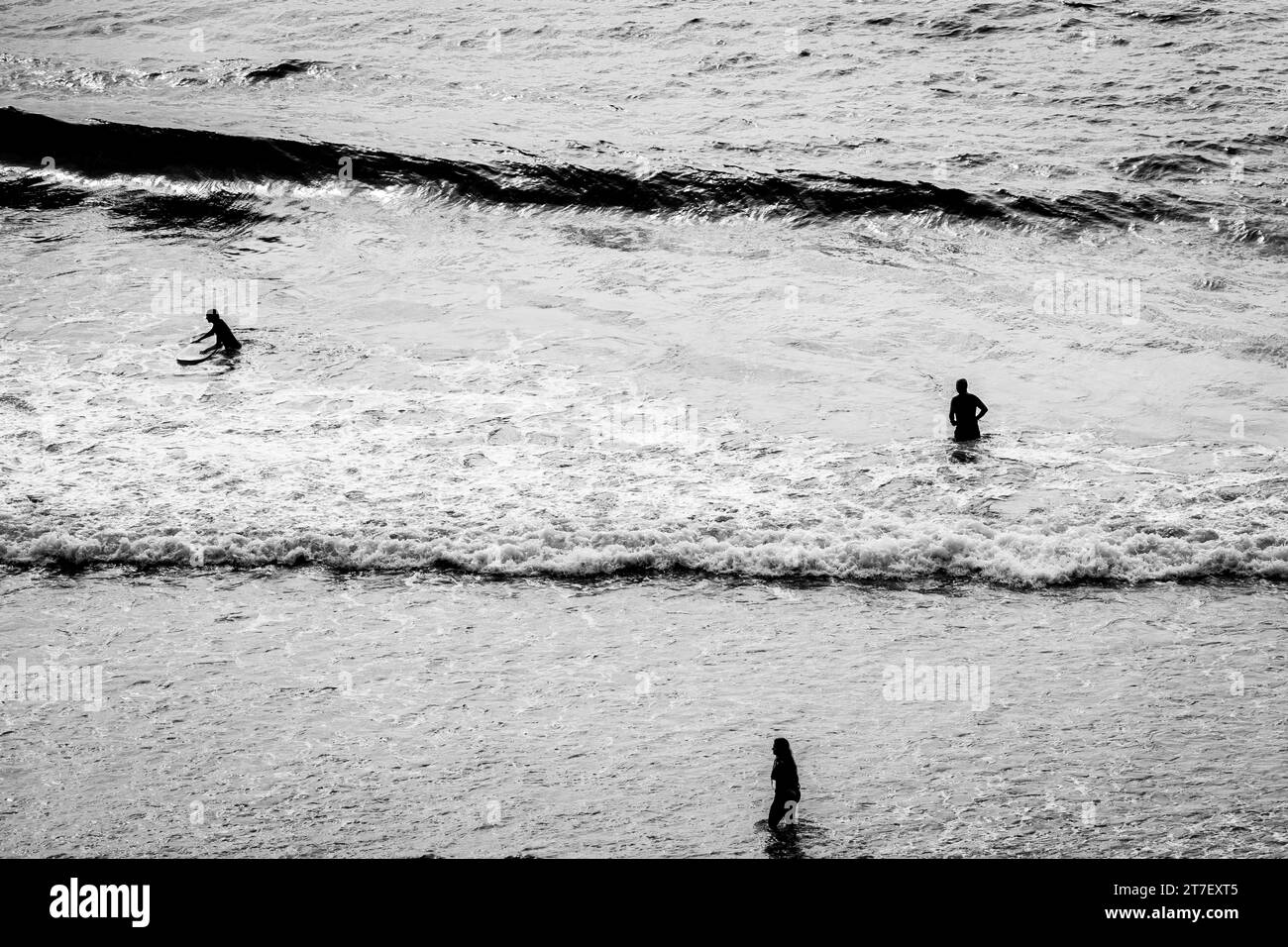 Coastal Harmony: Aerial View of Three Surfers Creating a Triangular Pose, Riding Waves with Precision and Unity Stock Photo