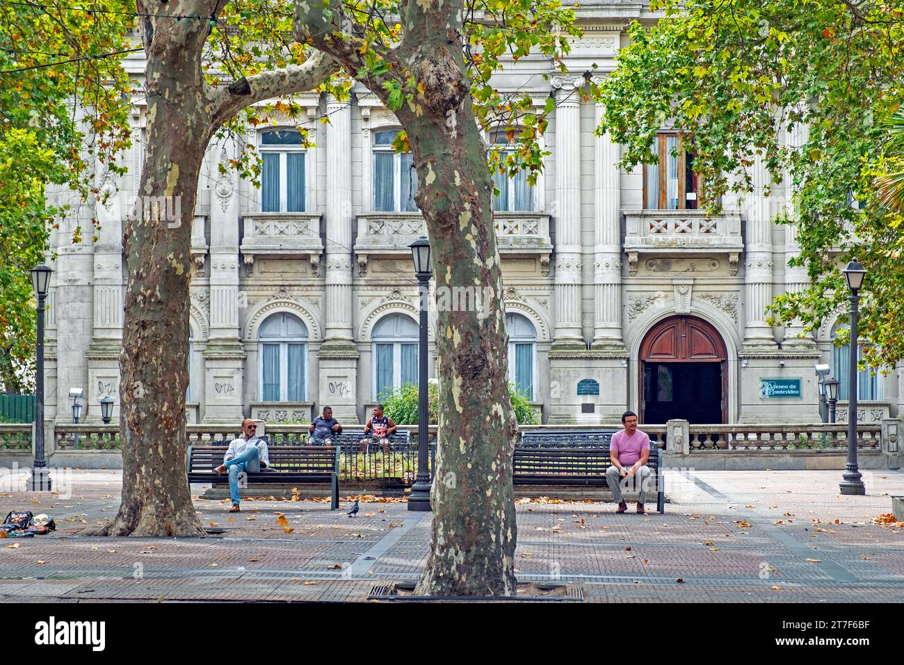 Locals resting on benches in front of the Ateneo de Montevideo at the Plaza de Cagancha in the barrio Centro at Montevideo, Uruguay, South America Stock Photo