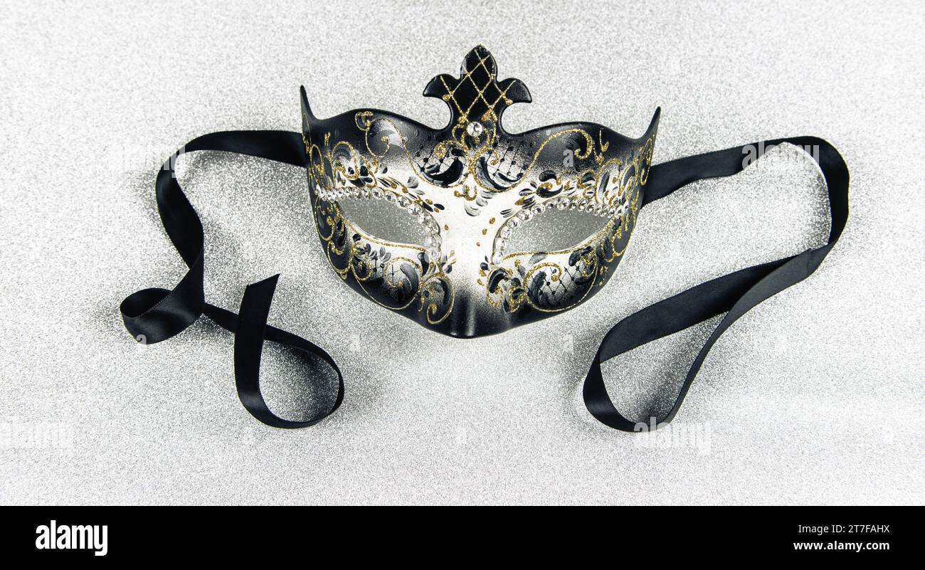 Carnival mask with black ribbon on silver shiny background. Close-up. Stock Photo