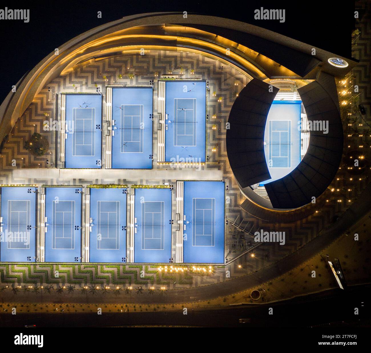 Aerial view of a nighttime tennis court, illuminated by bright stadium