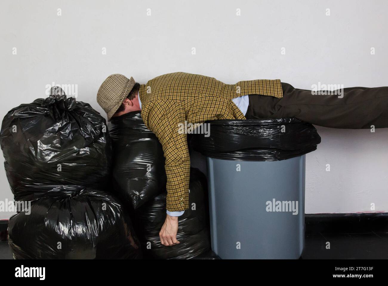 https://c8.alamy.com/comp/2T7G13F/portrait-of-man-in-ugly-suit-lying-atop-trash-can-and-pile-of-trash-bags-concept-of-over-a-barrel-man-thrown-away-2T7G13F.jpg