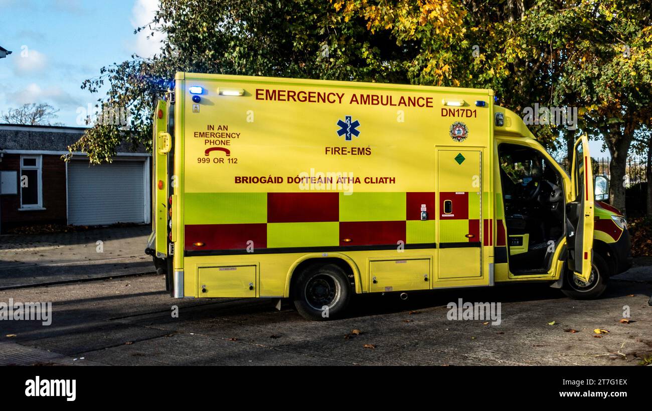 Bright yellow emergency Dublin Fire Brigade ambulance with open doors parked under autumn trees, ready for urgent medical services. Stock Photo