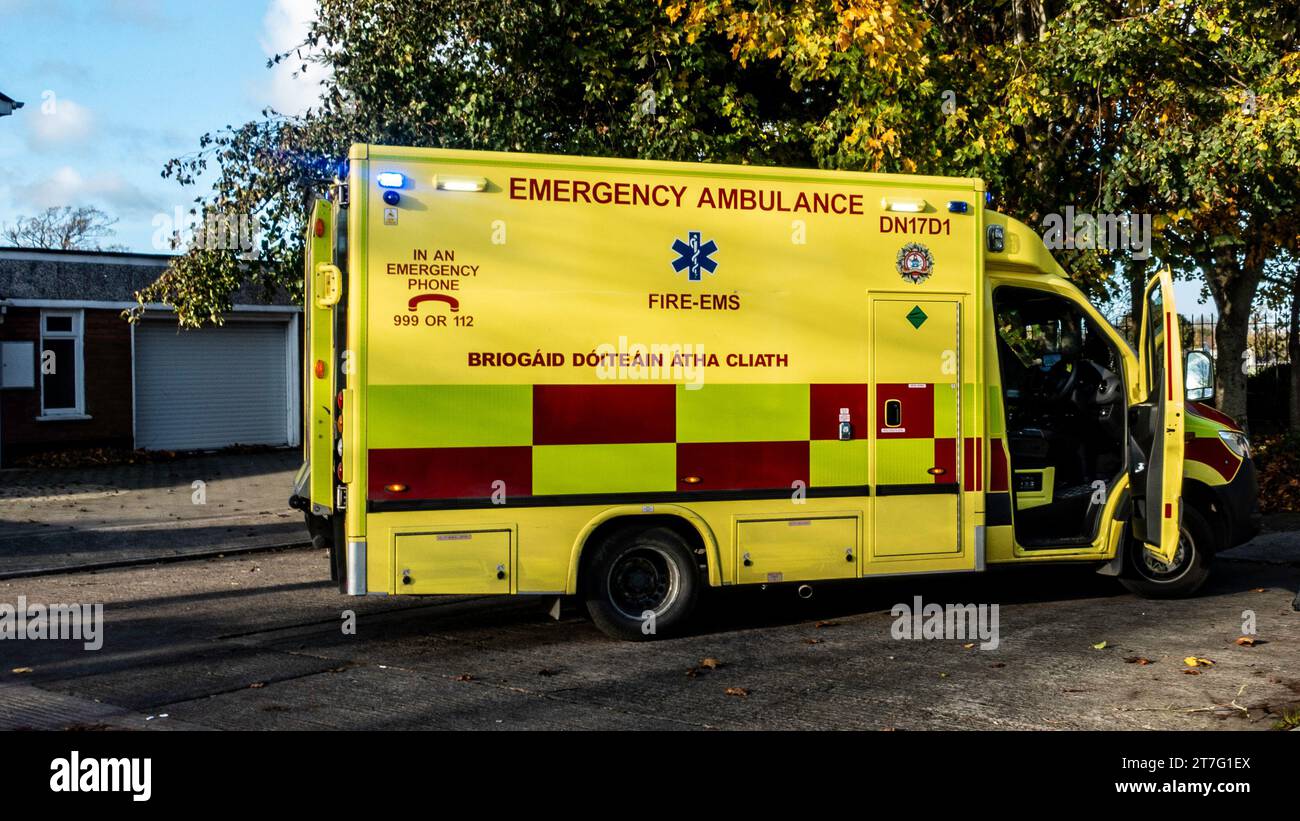 Dublin Fire Brigade emergency ambulance parked roadside with rear door open, bright yellow and red livery under autumn trees, serving FIRE-EMS respons Stock Photo