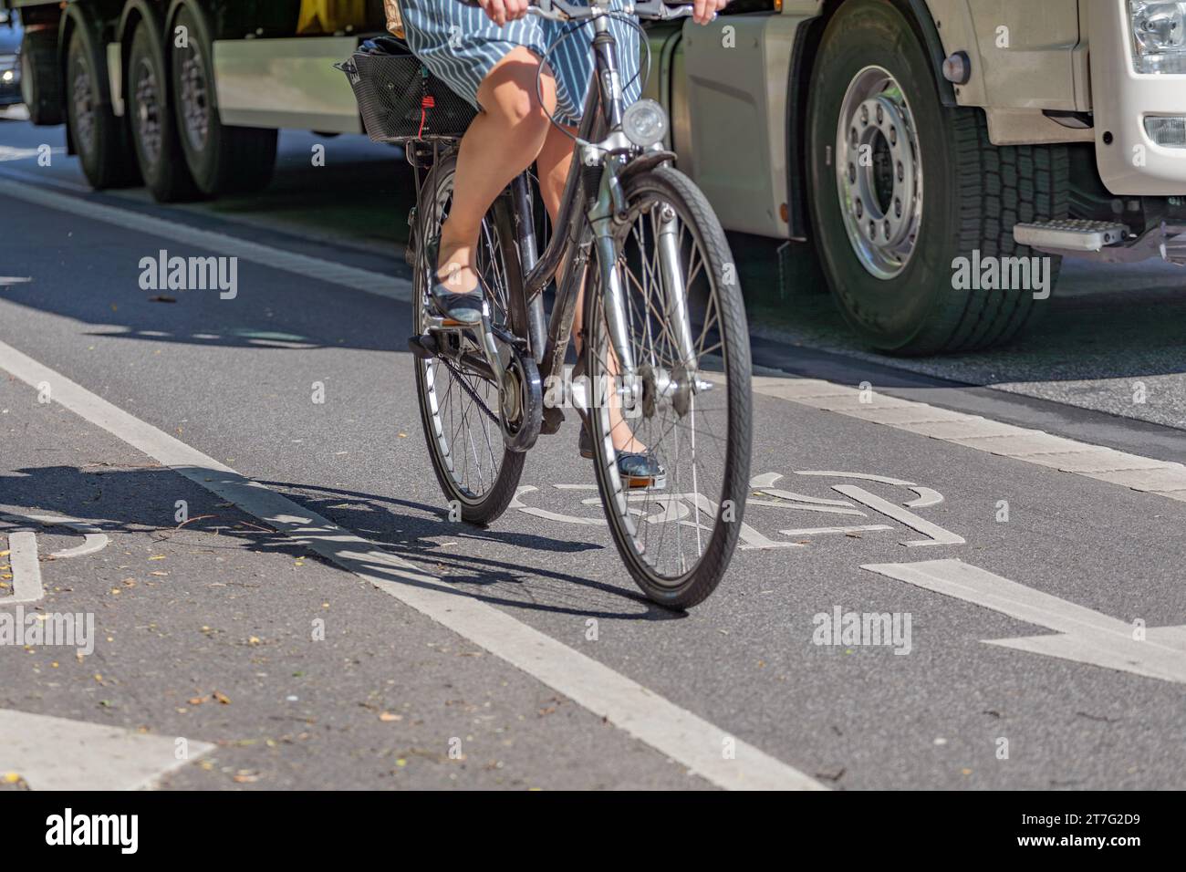 Female cyclist in bike lane next to truck Stock Photo