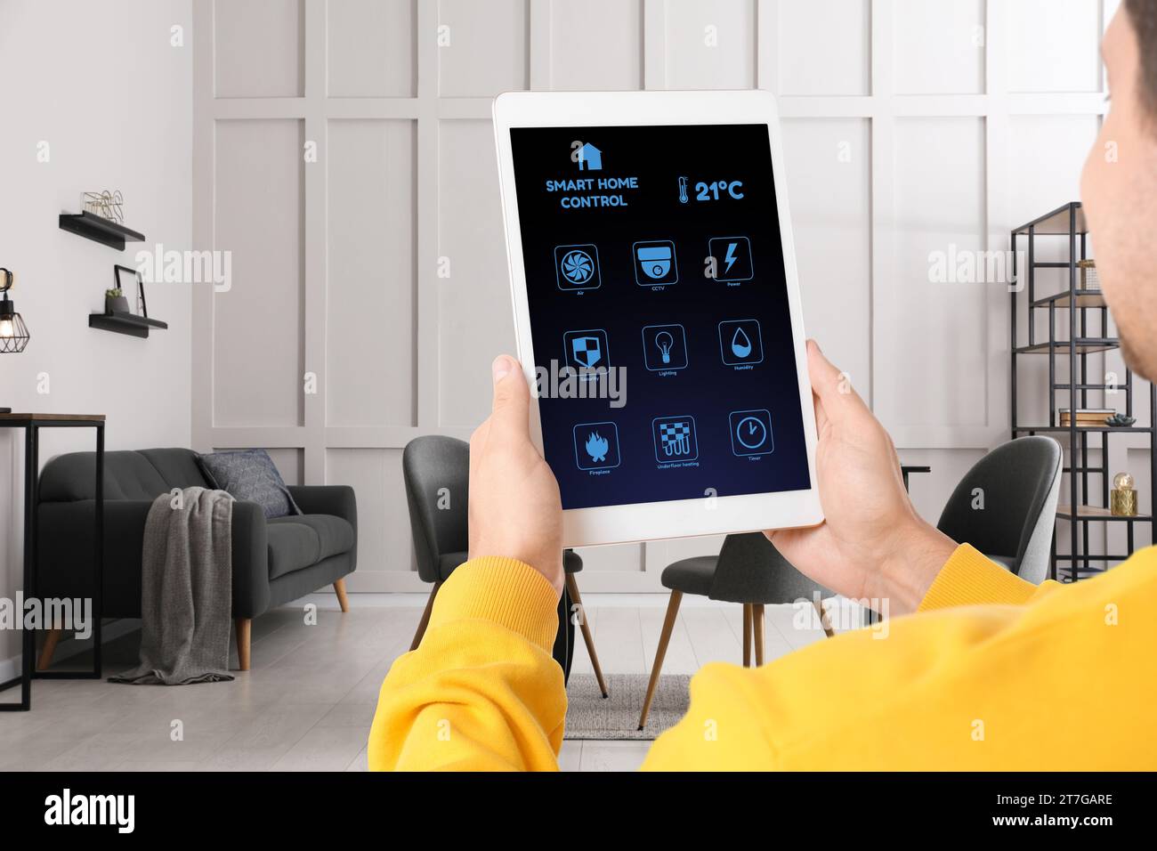 Man using smart home control system via application on tablet indoors, closeup Stock Photo