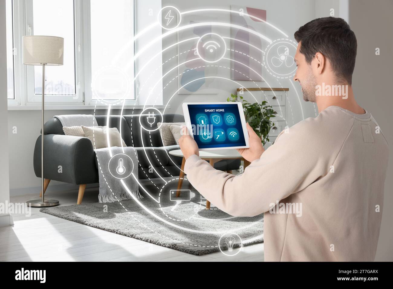 Man using smart home control system via application on tablet indoors. Scheme with icons around device Stock Photo