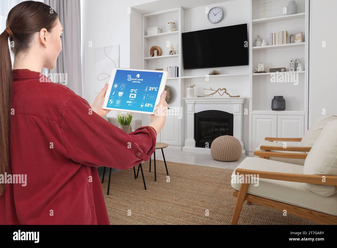 Woman using smart home control system via application on tablet indoors Stock Photo