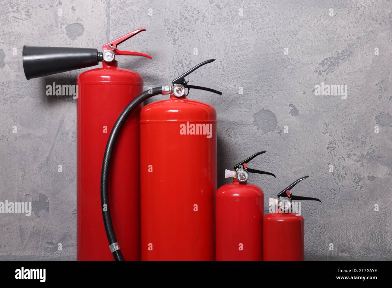 Four red fire extinguishers near grey wall Stock Photo Alamy
