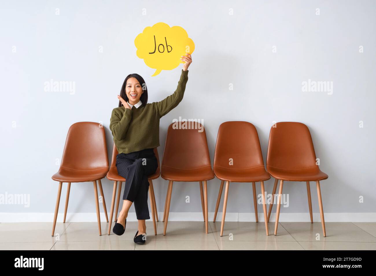 Asian businesswoman holding speech bubble with word JOB near light wall Stock Photo