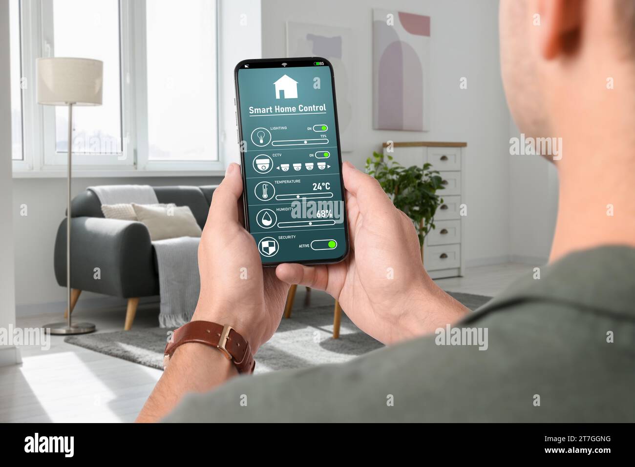 Man using smart home control system via application on mobile phone indoors, closeup Stock Photo
