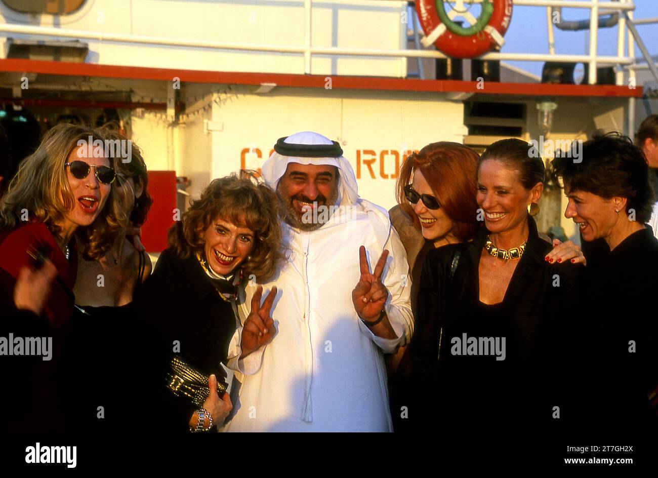 A group of American tourists pose for a photo with Sheik Feisal aboard an oil tanker in the Persian Gulf at Dubai, UAE Stock Photo