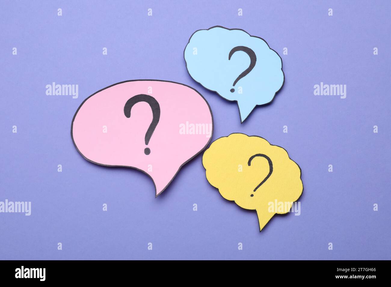 Different paper speech bubbles with question marks on violet background, flat lay Stock Photo