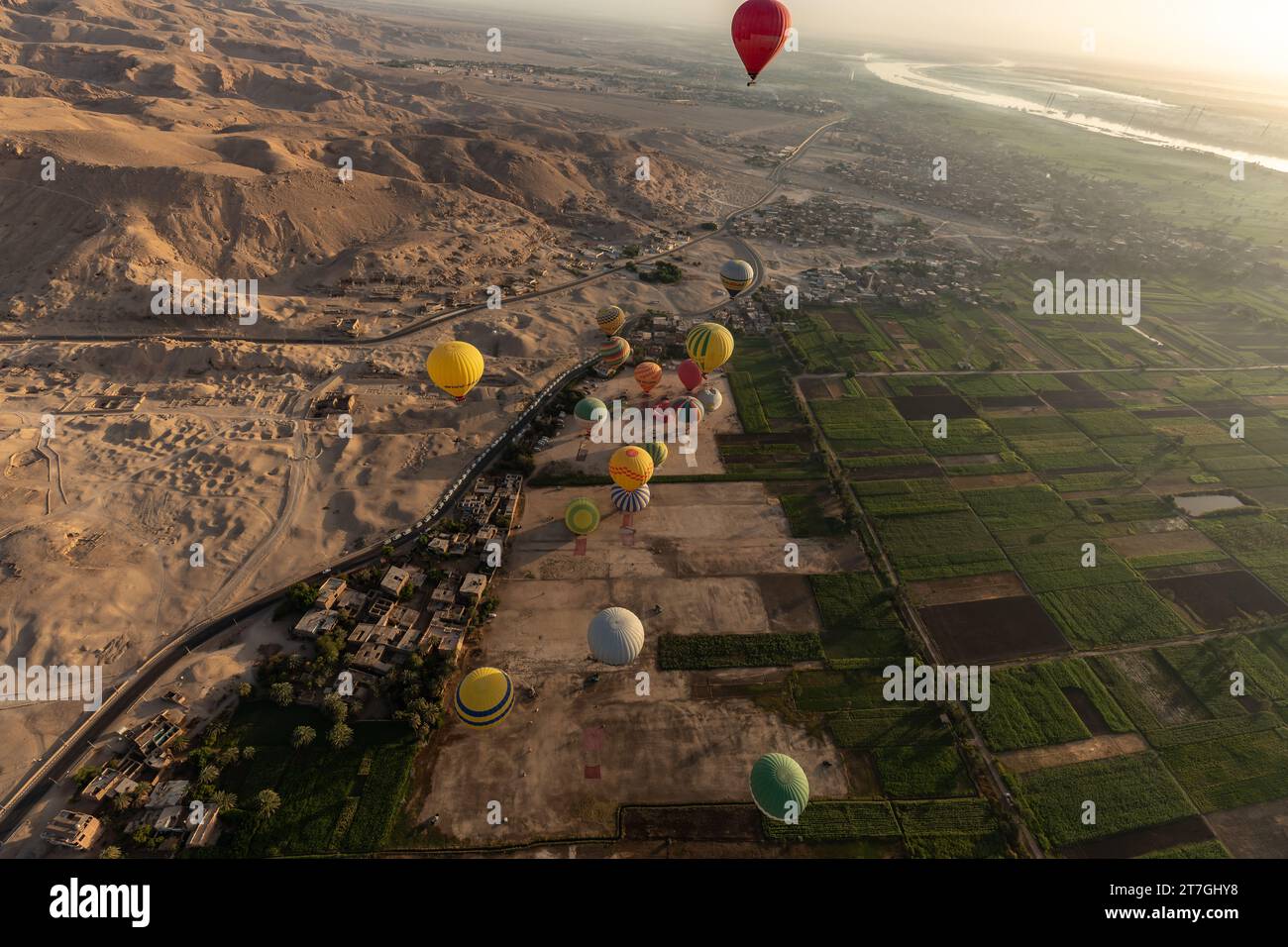 Aerial view of hot air balloons flying over desert landscape of Valley of the kings and farms in the fertile Nile River valley Stock Photo