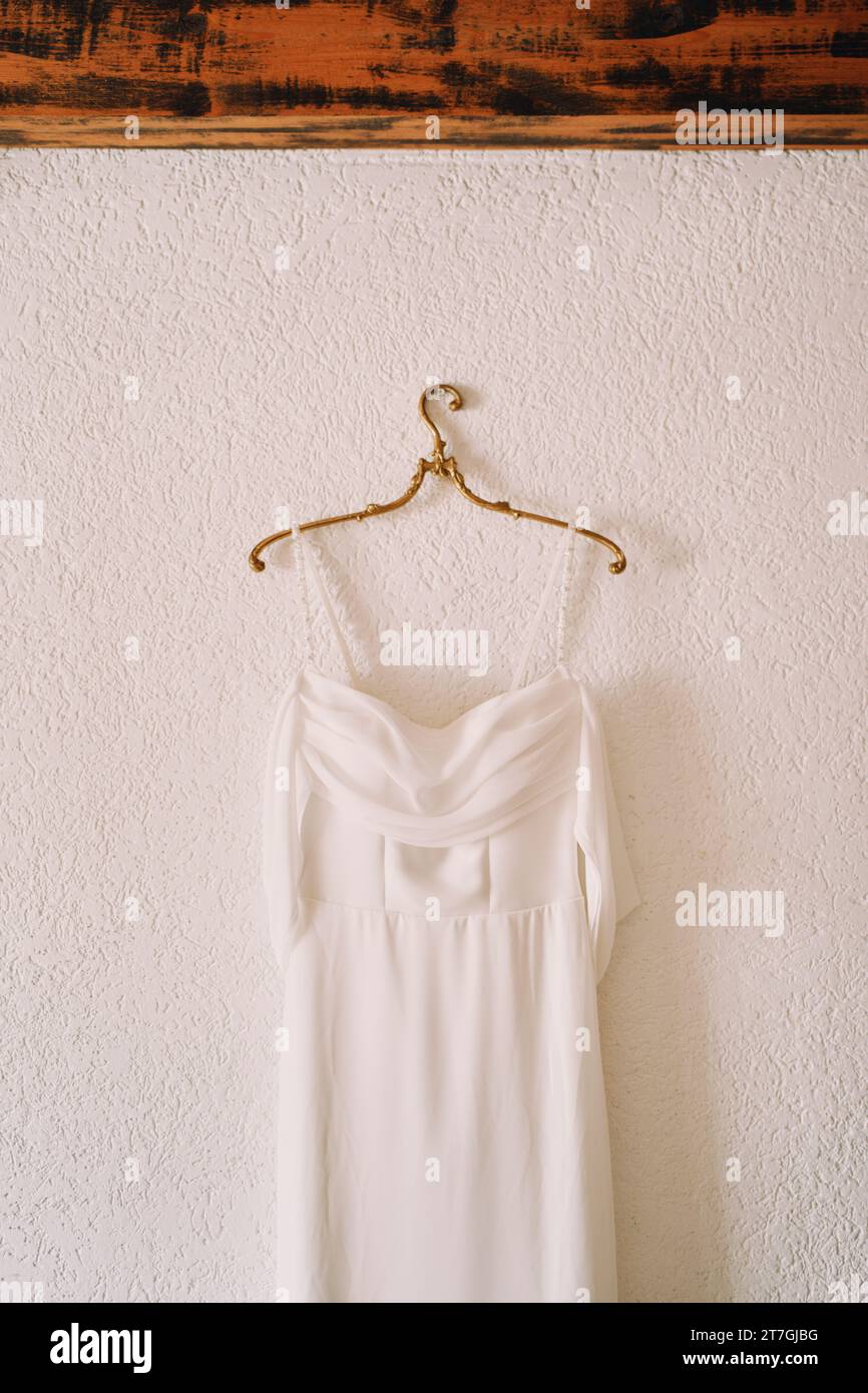 Wedding dress with straps hanging on a hanger on a white wall Stock ...