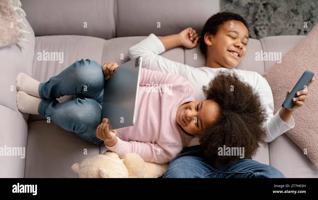 Siblings using tablet mobile home 3 Stock Photo