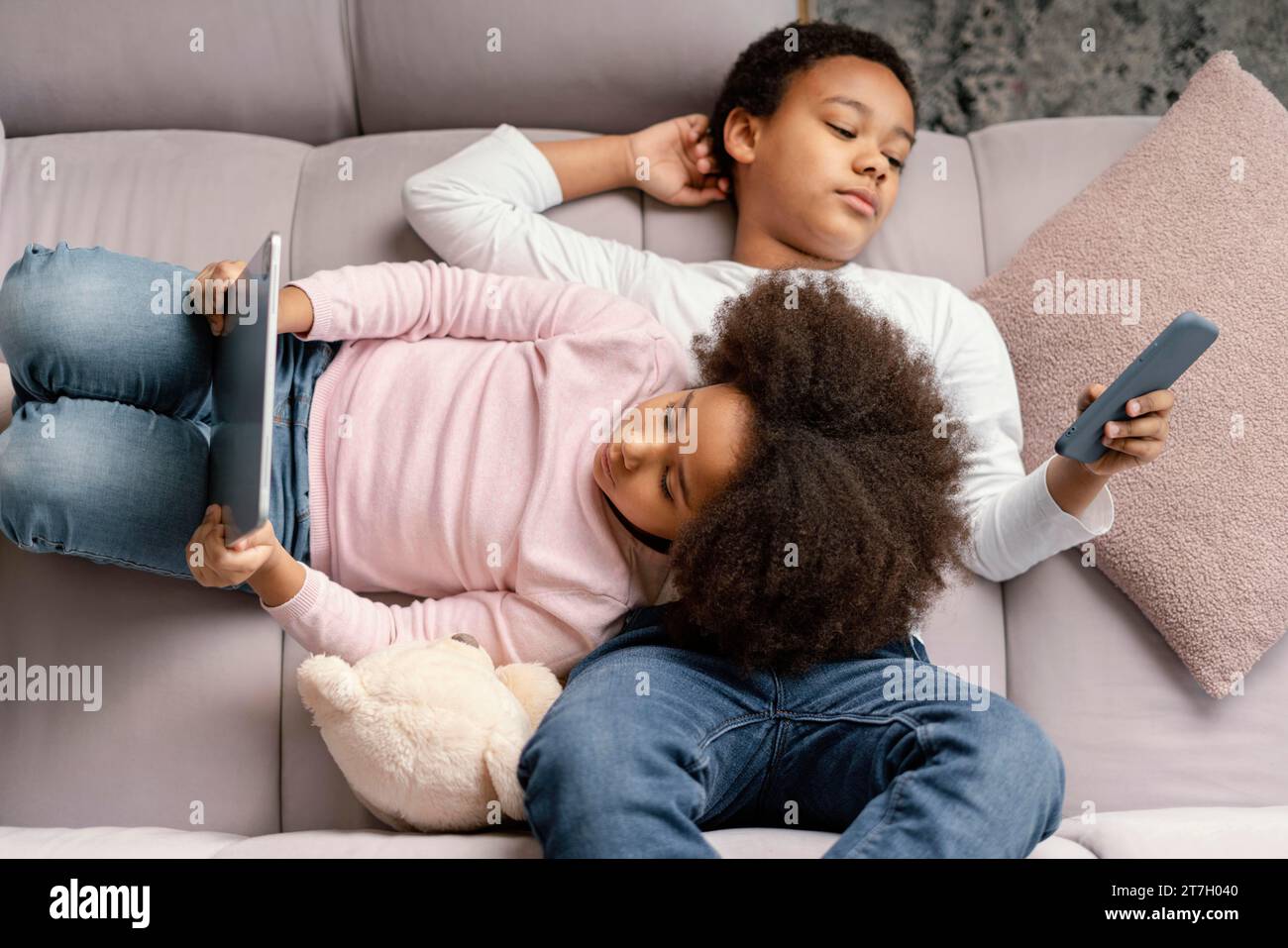 Siblings using tablet mobile home 2 Stock Photo
